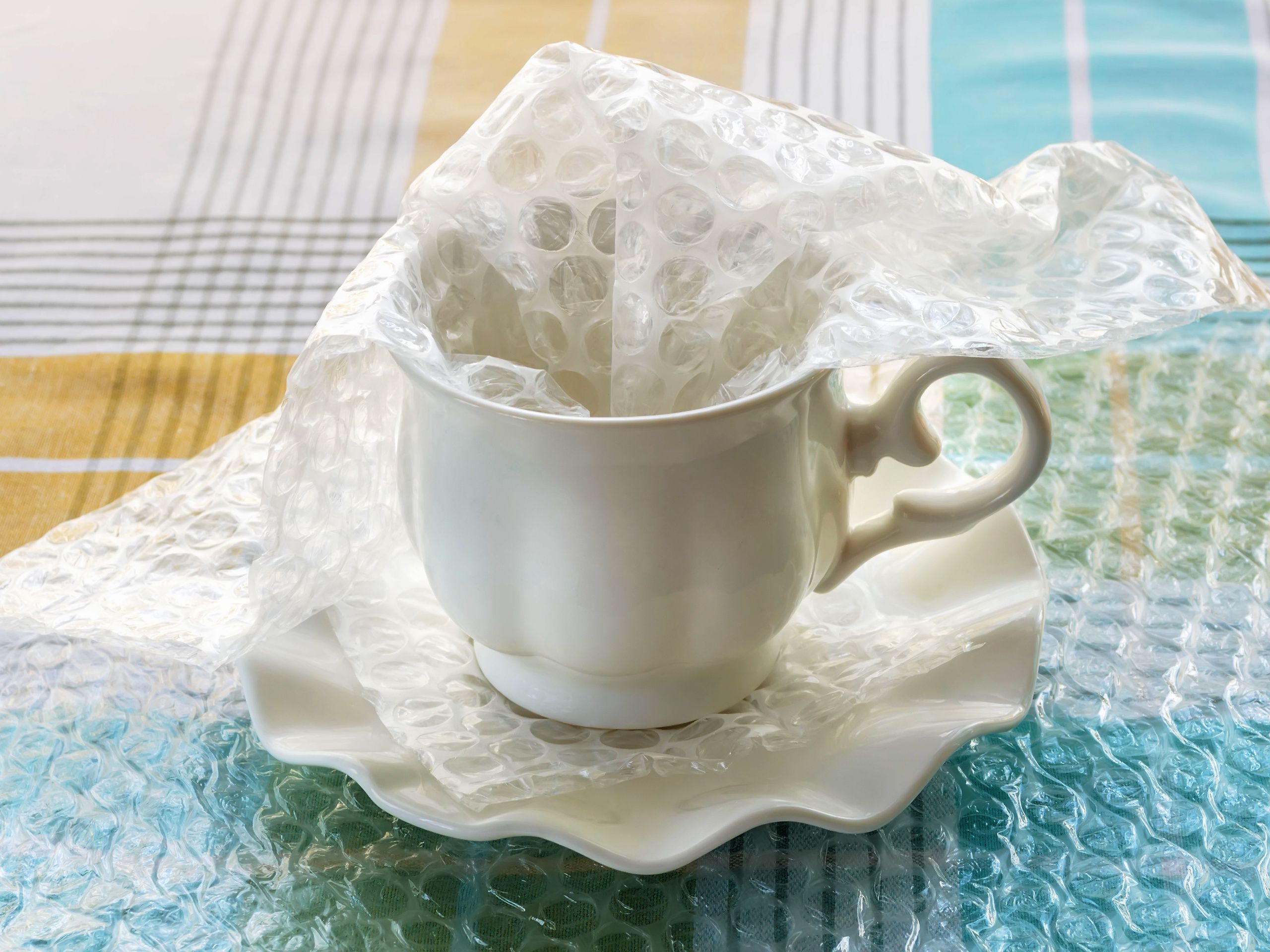Packing fragile cup and saucer with bubble wrap